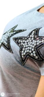 abito asimmetrico grigio con maniche corte e due applicazioni a forma di stella sul petto